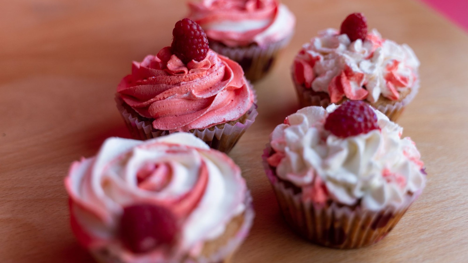 Homemade cupcakes with raspberry frosting on a wooden board